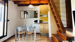 A compact kitchen with a wooden staircase, a dining area with chairs, and a large mirror on the wall. - Bellevue by Interhome (Sierra Nevada)