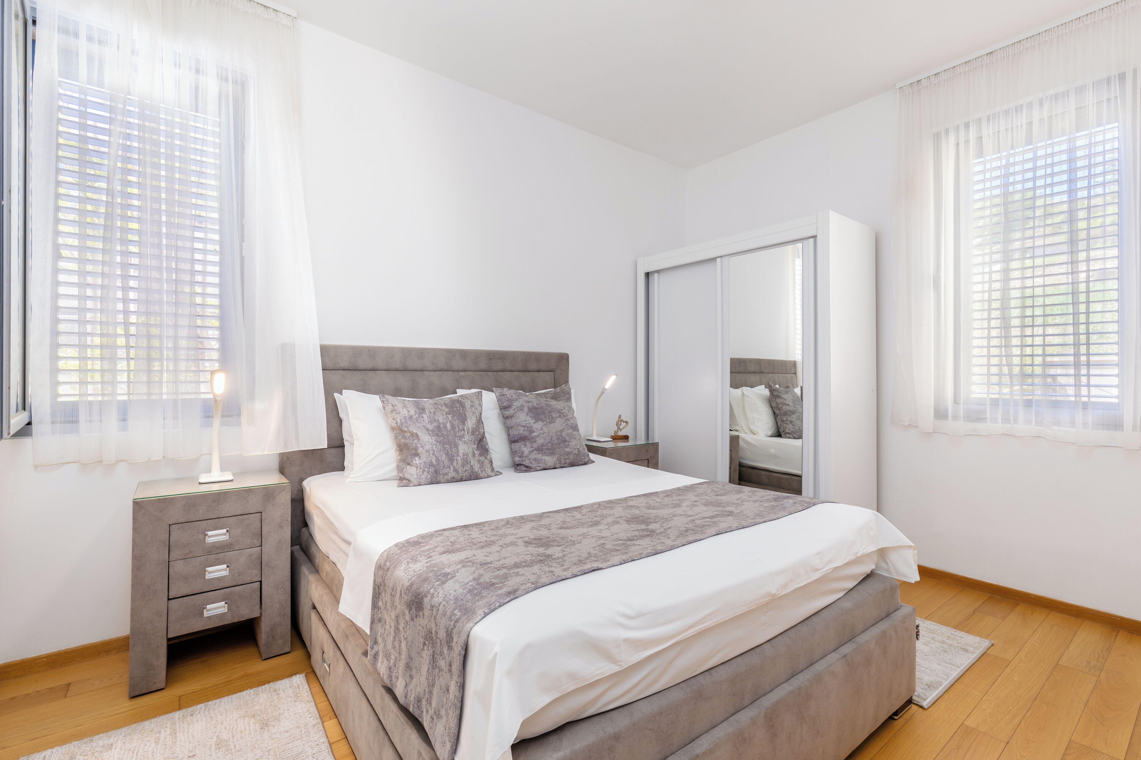 Une chambre à coucher comprenant un lit, une table de chevet, une commode et un miroir.