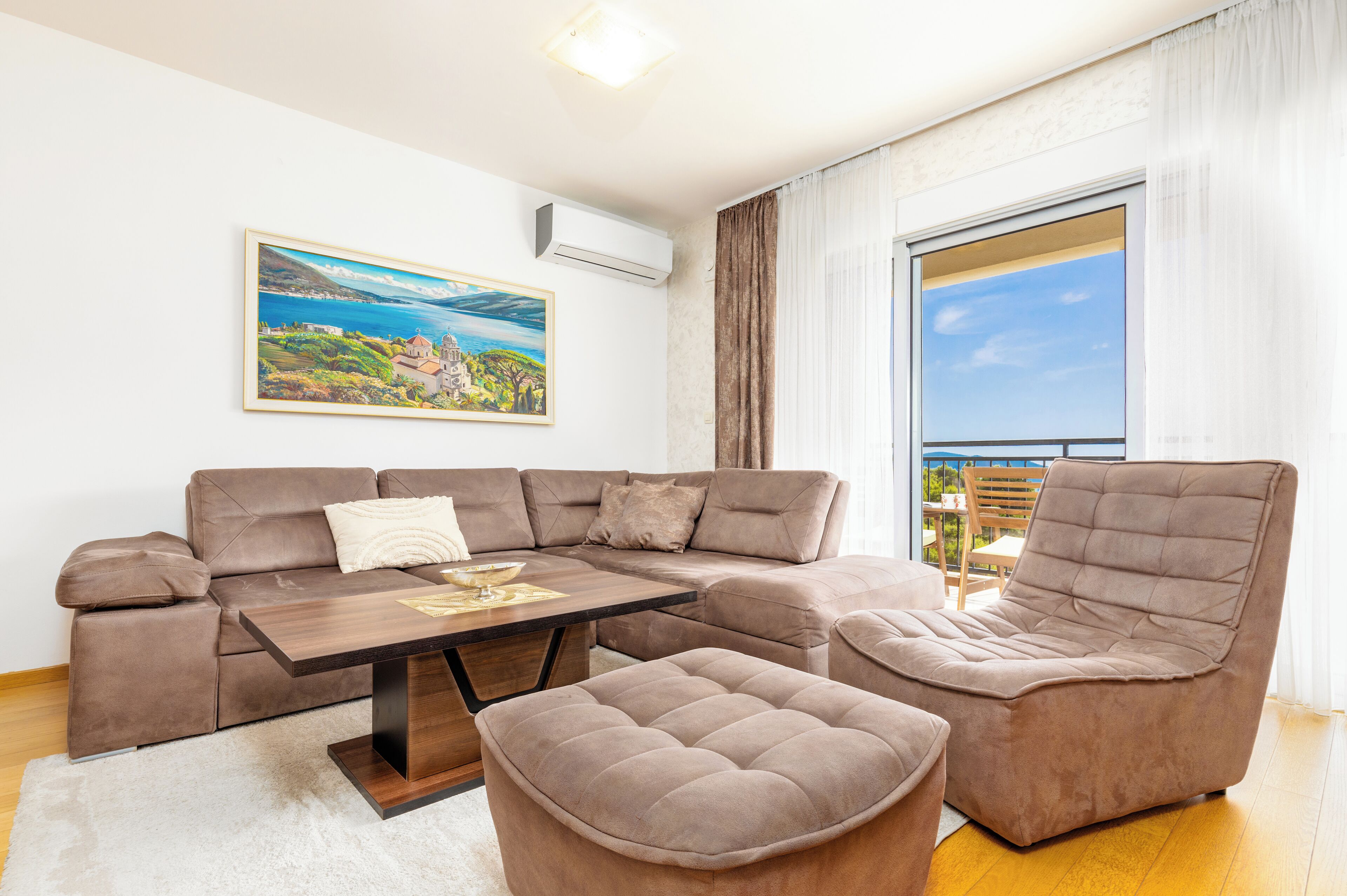 A modern living room with a sectional sofa, a chaise lounge, a coffee table, and a large window with curtains.
