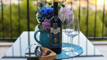 Una botella de vino Vranac, una copa y un sacacorchos de madera sobre una mesa con una servilleta azul, frente a un balcón con vistas.