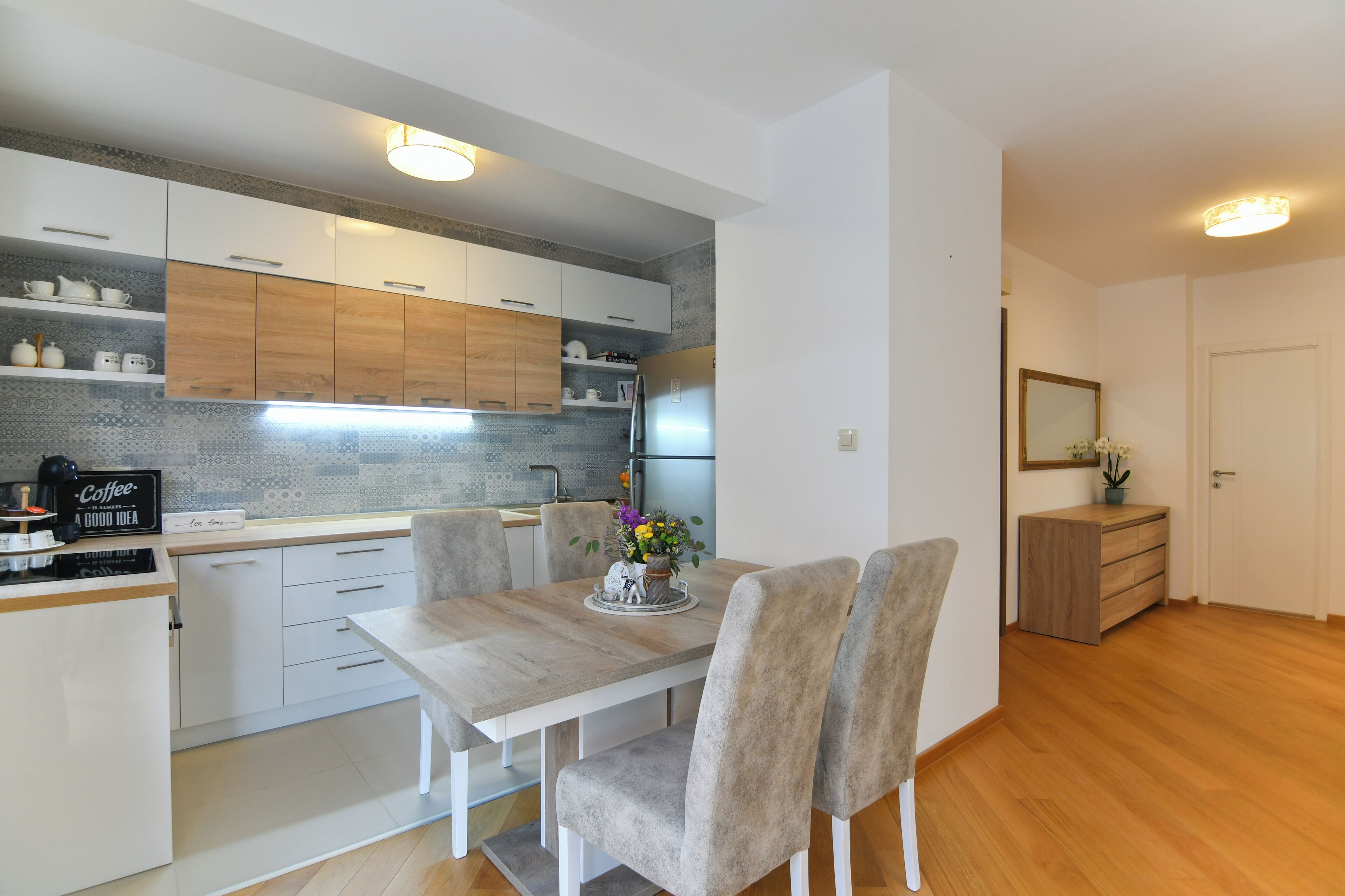 A modern kitchen with white cabinets, a wooden countertop, and a dining table with chairs.