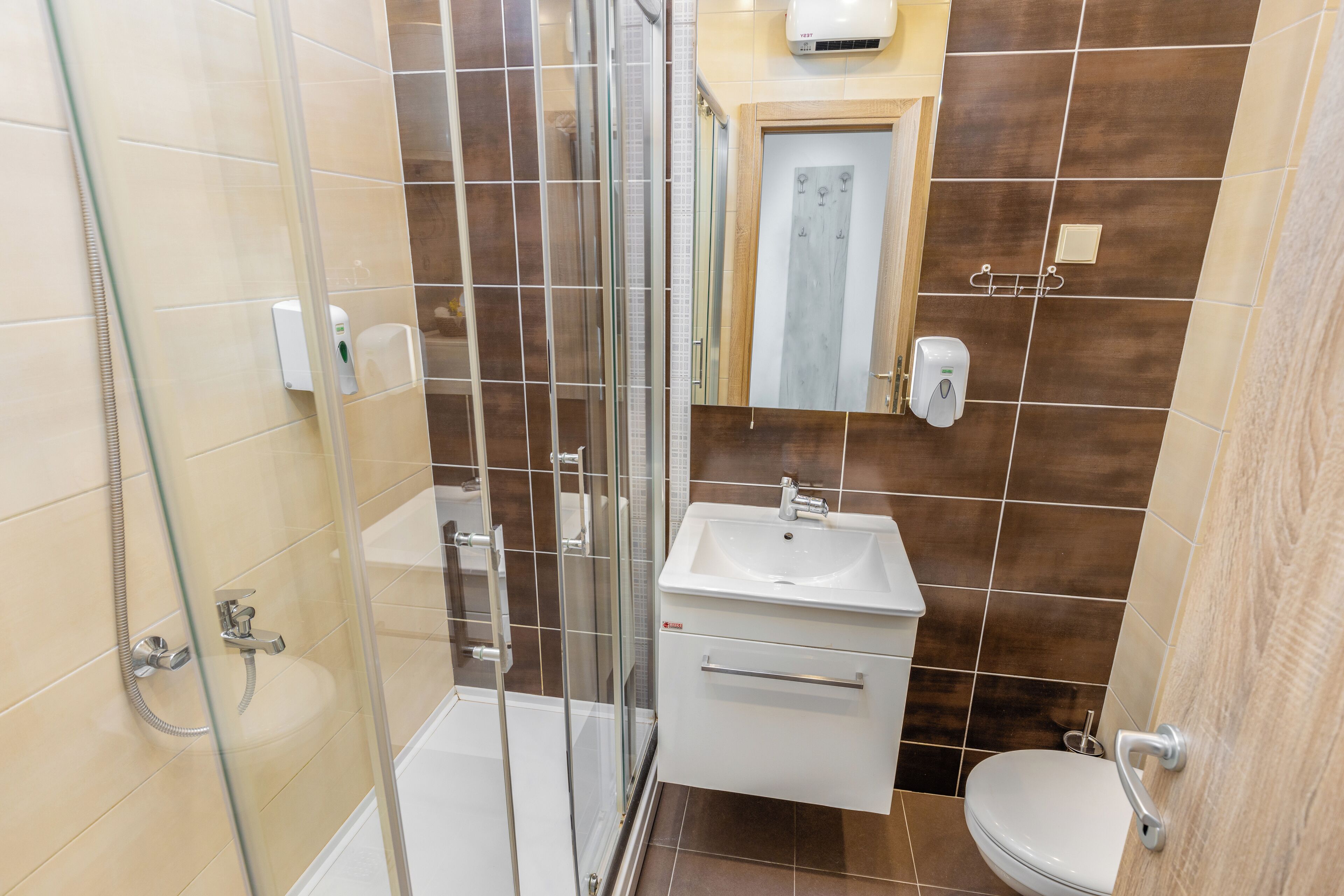 Ein Badezimmer mit Duschkabine aus Glas, Waschbecken und Toilette.