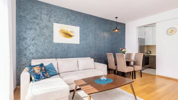 A modern living room with a sofa, coffee table, and dining area.
