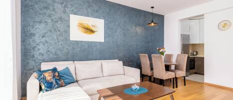 A modern living room with a sofa, coffee table, and dining area.