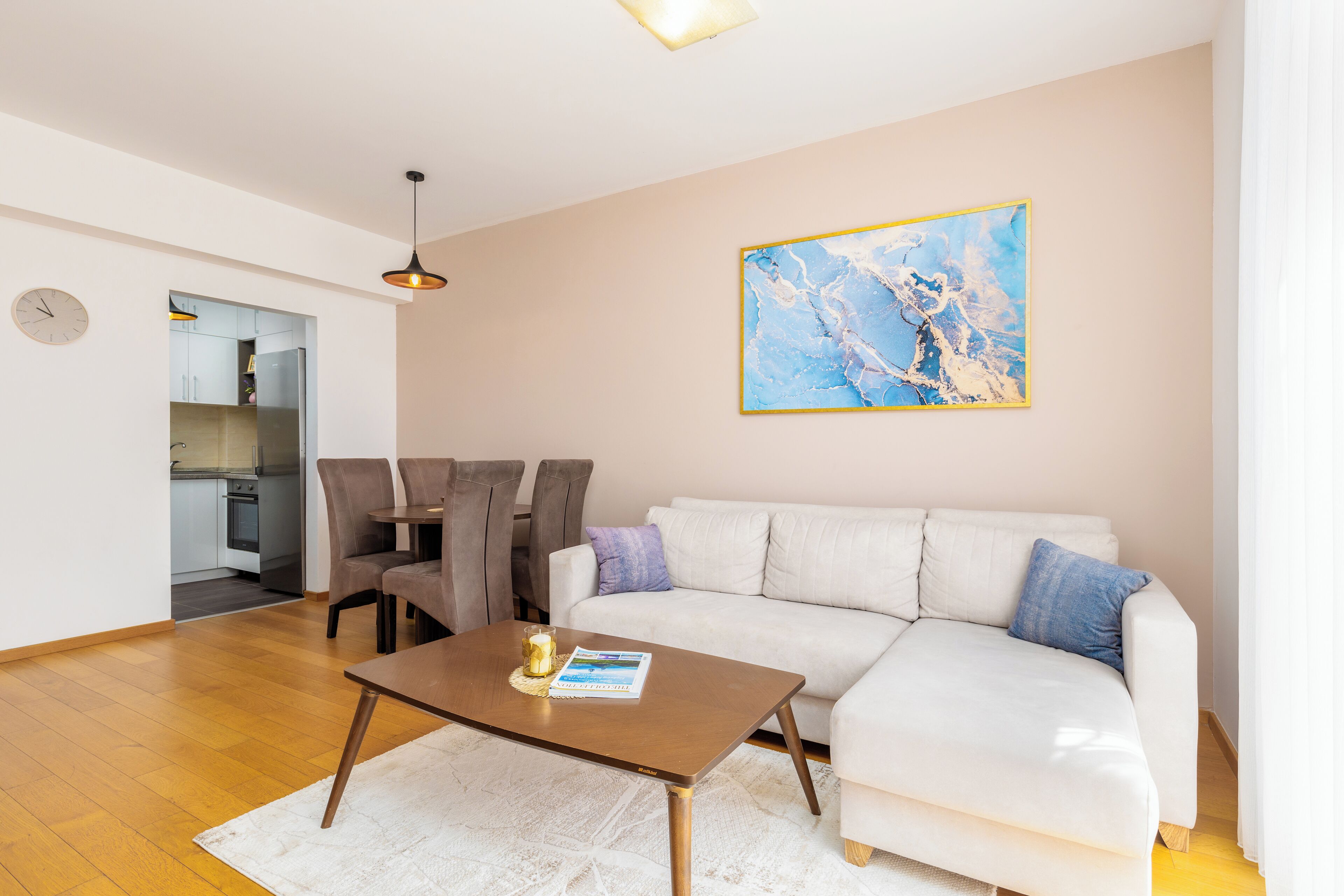 A modern living room with a white sofa, a coffee table, and a dining area with chairs.