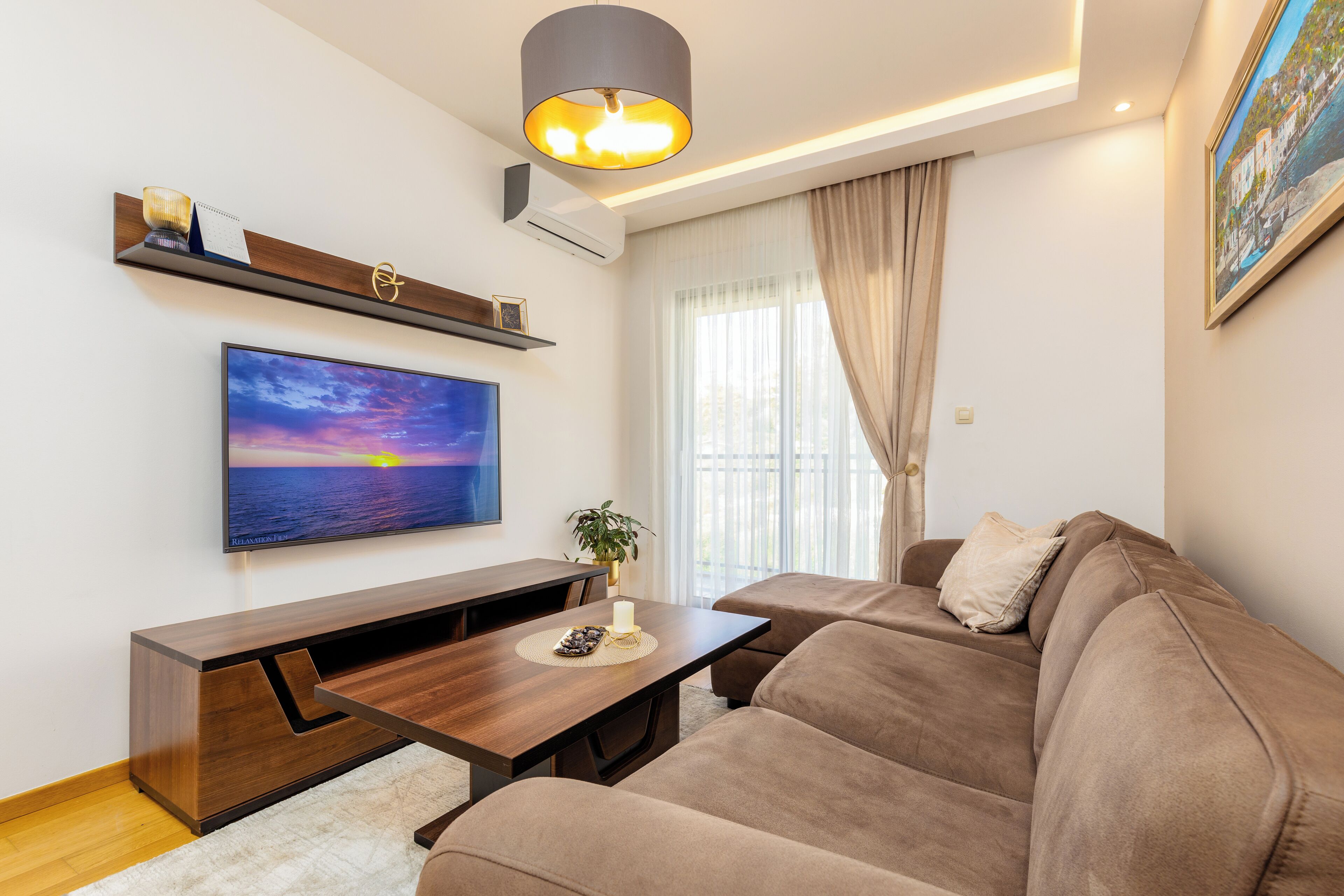 Ett modernt vardagsrum med en soffa, ett soffbord och en platt-TV som är monterad på väggen.