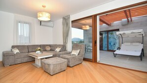 Een moderne woonkamer met een zithoek, een salontafel en een schuifdeur naar een buitenruimte met een pergola.