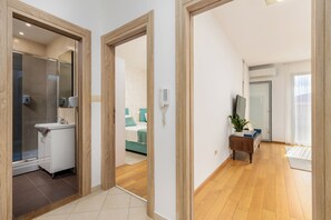 Une chambre d’hôtel avec une salle de bain, un lit, un plancher en bois et une petite table d’appoint en bois.