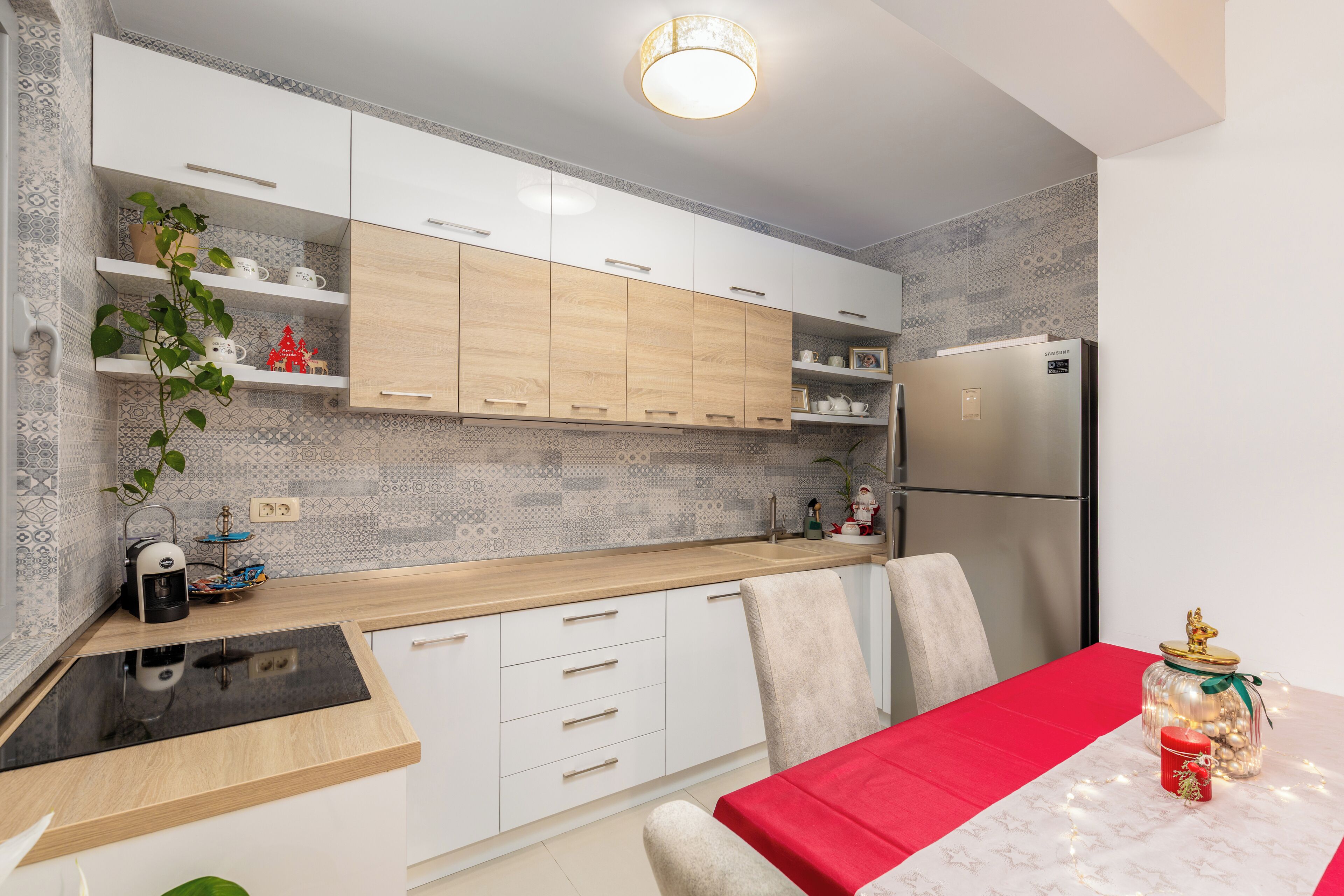 A modern kitchen with white cabinets, a wooden countertop, and a red tablecloth.