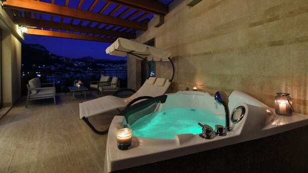 Een wellnessruimte met een jacuzzi, lounge fauteuils en een kaars.