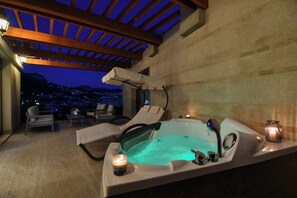 Uma área de spa com hidromassagem, espreguiçadeiras e uma vela.