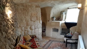 Une pièce aux murs de pierre, avec un canapé, un tapis à motifs et une cheminée.