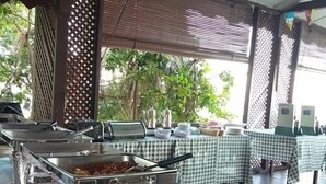 A buffet setup with stainless steel serving stations and a checkered tablecloth-covered table. - Johan's Place (Tioman Island)