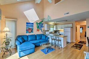 Relax in a spacious living area with a comfortable sofa and glass coffee table, surrounded by a modern kitchen and open-plan design.