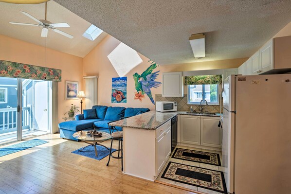 Cozy living space with a kitchenette, sofa, and small island featuring a microwave and refrigerator.