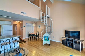 Cozy living space with a central kitchen, dining area, and bar, featuring a spiral staircase and comfortable seating.