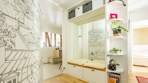 A modern room with a built-in bed, white shelving with plants, and a large wall mural.