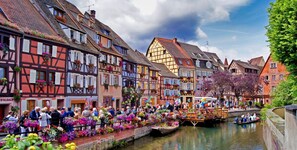 Uma cidade histórica europeia com ruas estreitas flanqueadas por casas coloridas de enxaimel.