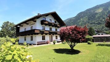 A two-story building with a balcony, surrounded by a well-maintained lawn and a mountain backdrop.