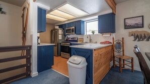 Eine Küche mit blauen Schränken, einer Mikrowelle, einem Kühlschrank und einer Holztheke.