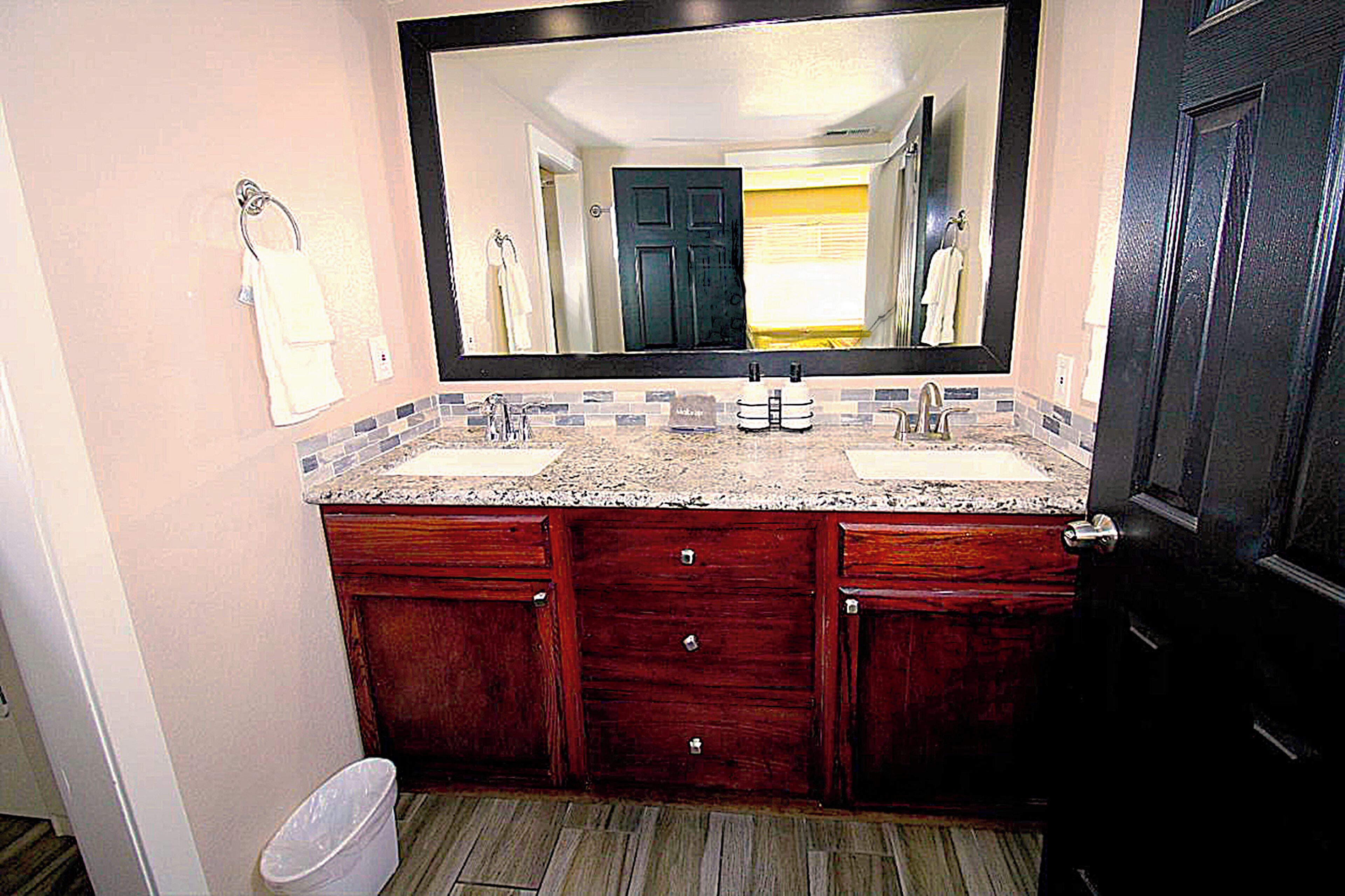 Une salle de bain avec deux lavabos, un grand miroir et des meubles en bois.