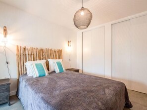 A bedroom with a bed, a nightstand, a wall-mounted light, and a wardrobe.
