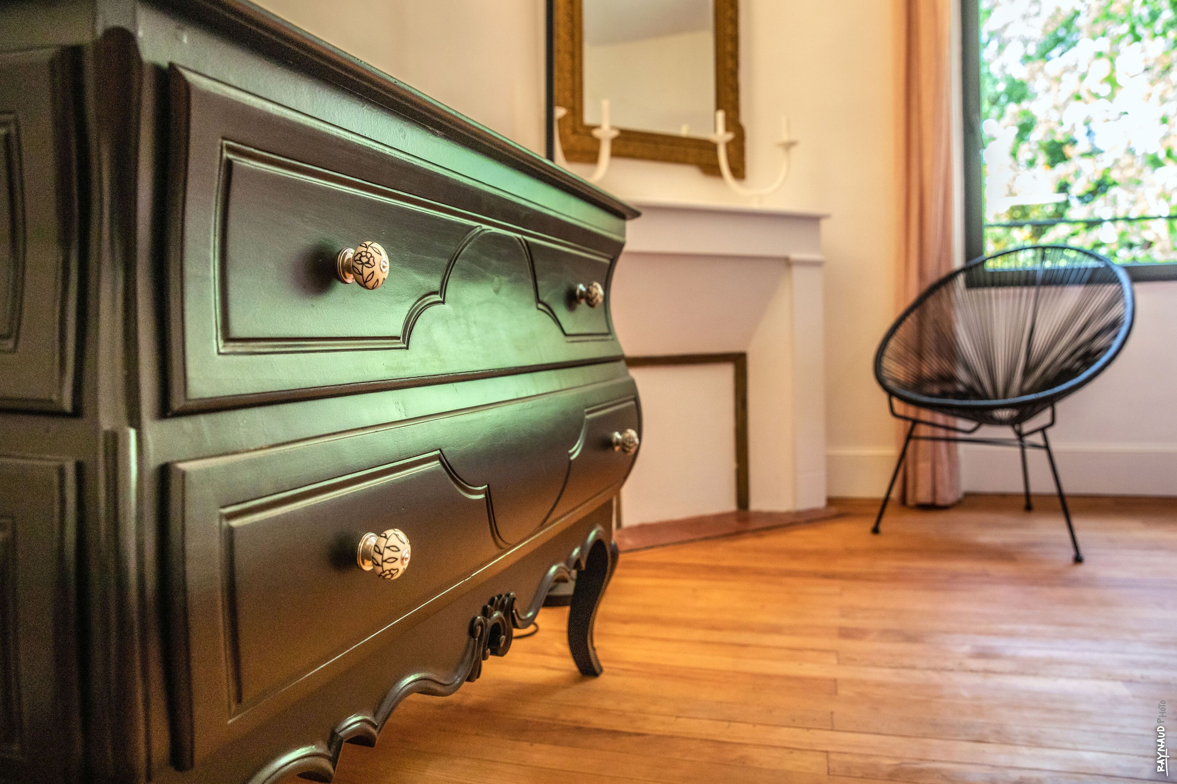 A wooden dresser with ornate handles and a mirror above it.