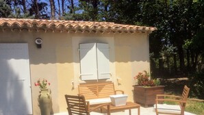 Une petite terrasse extérieure avec des meubles en bois, une porte blanche et un toit recouvert de tuiles.