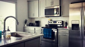 A modern kitchen with stainless steel appliances, a microwave, oven, and a refrigerator.