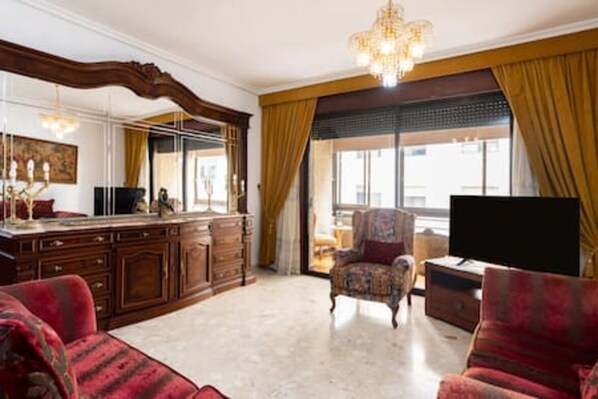 A spacious living room with a large TV, a fireplace, and a comfortable sofa.