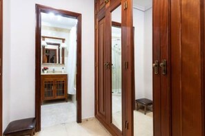 A hallway with wooden doors leading to a bathroom with a mirror and a sink.