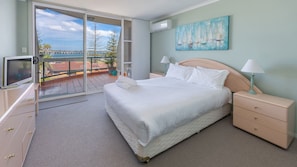 A bedroom with a bed, bedside tables, a TV, and a balcony with a view of the sea. - Castillo Del Mar 10 - Overlooking the Lake (Tuncurry)