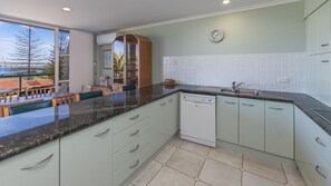 Eine moderne Küche mit Geschirrspüler, Spüle und Essbereich mit Aussicht.