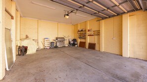 Eine geräumige Garage mit Betonboden, Deckenventilator und festinstalliertem Projektor.