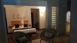 Une chambre à coucher avec un lit, deux fauteuils en osier, une petite table et une lampe de chevet.