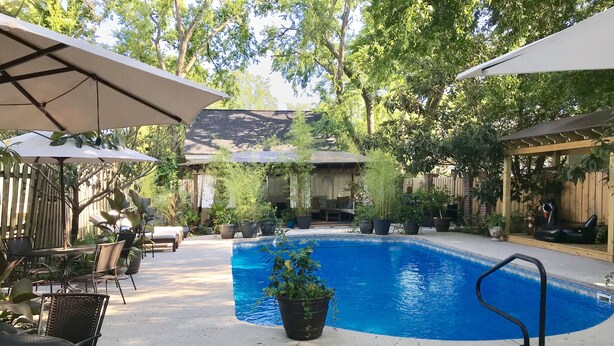 Ein Swimmingpool mit einer umlaufenden Terrassenanlage, inklusive Sitzgelegenheiten und Sonnenschirmen.