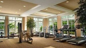 A spacious gym with cardio machines, weight equipment, and large windows offering natural light. - One bedroom in amazing luxury condo. BEACH PASS INCLUDED! (Boynton Beach)