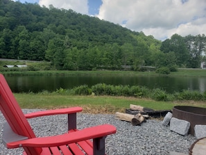 A red Adirondack chair by a lake with a forested hill in the background. - Rivers Edge of the West Branch Delaware River w Private Boat Launch (Deposit)
