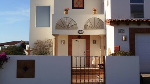 Ein zweistöckiges Haus mit weißer Fassade, einem Ziegeldach und einem Eingangstor.