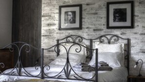 A bedroom with a metal bed frame, a brick-patterned wall, and framed pictures. - SARKEEP - Villa immersed in the Taurasi vineyards (Luogosano)