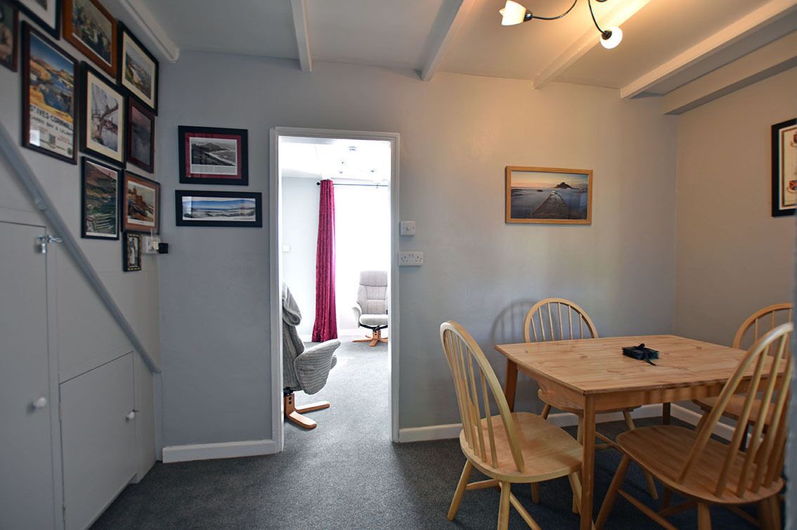 A dining area with a wooden table and chairs, a red curtain, and framed pictures on the wall.