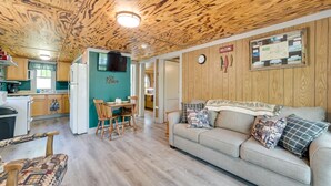 Ein gemütliches Interieur mit Holzbalkendecke, einer Küchenzeile, einem Essbereich und einer Couch mit gemusterten Kissen.