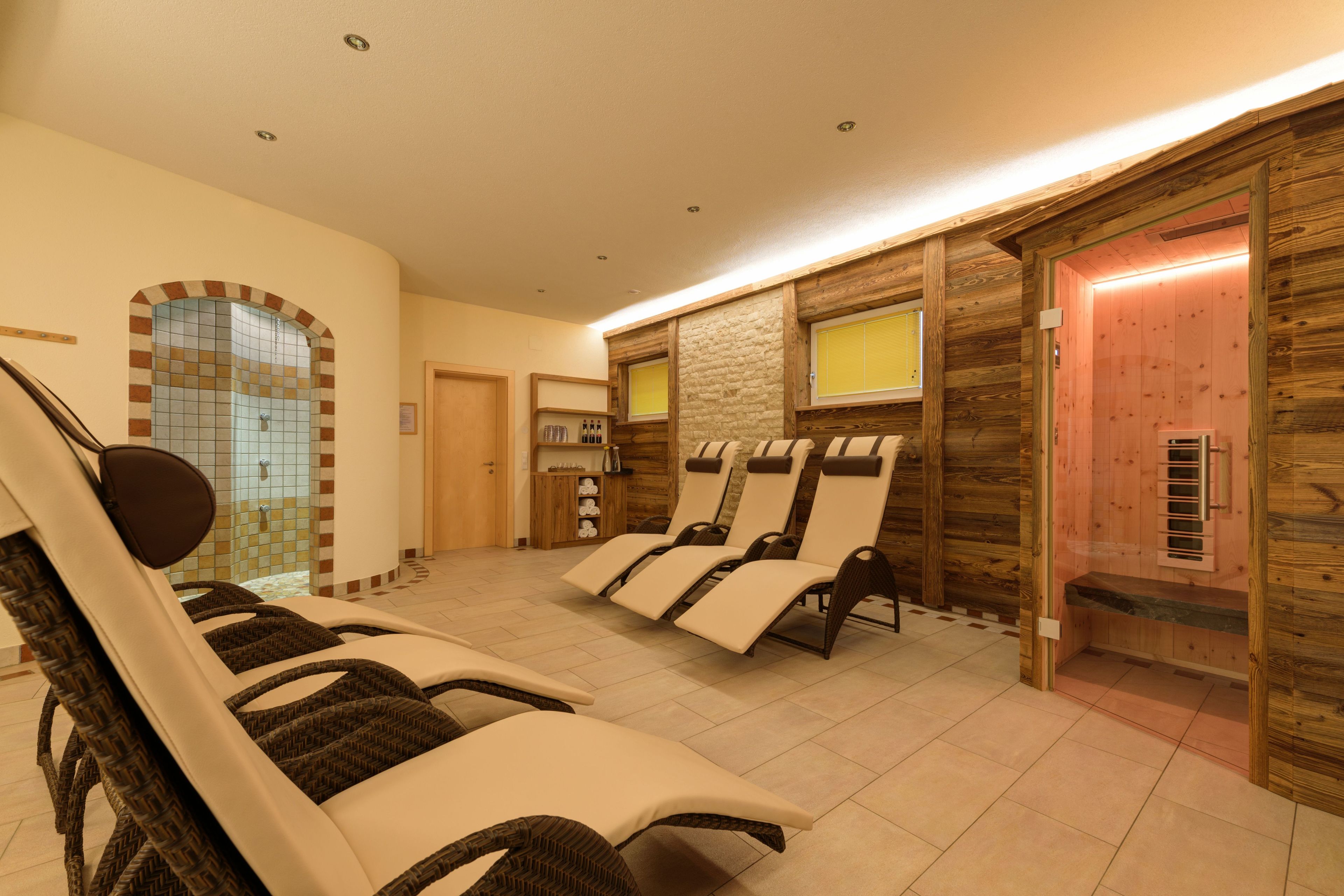 A spa area with reclining chairs, a small reception desk, and a wooden wall with a window.