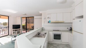 A compact kitchen with a built-in oven, a sink, and a small dining area with a table and chairs. - Horizons 1 - Location, location, location! (Forster)