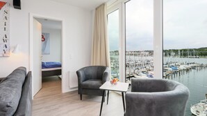 Une chambre moderne dotée d’une grande fenêtre donnant sur un port de plaisance.