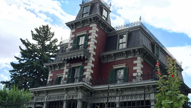 A Victorian-style building with a steeply pitched roof, ornate iron railings, and a prominent tower with a balcony. - Art Inspired Cottage just 1 block from Main Street (Trinidad)