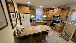 A modern kitchen with wooden cabinets, a granite countertop, a built-in oven, and a stainless steel refrigerator.