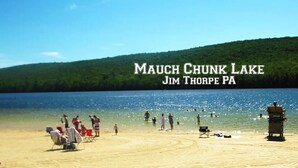 A beach scene at Mauch Chunk Lake with people swimming and sunbathing.