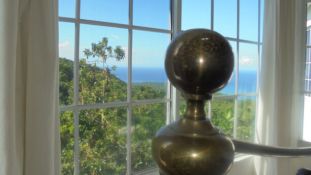 A window with a view of a lush landscape and the ocean. - Pearl Ocean Villa (Saint Margarets Bay)