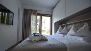 A hotel room with a large bed, a view of the outdoors, and a window with curtains. - Very nice 'villetta' in beautiful and quiet fully garden. (Bardolino)